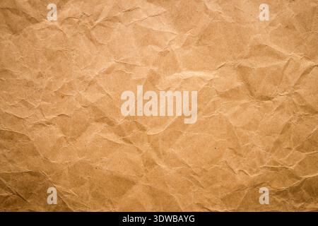 A close-up of crumpled craft paper with wrinkles and texture, creating a natural and rustic background. Perfect for use in design projects, packaging, Stock Photo