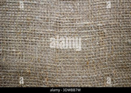 A close-up of a coarse linen fabric with a large canvas weave, showcasing its natural texture and rustic charm. The thick weave and organic Stock Photo
