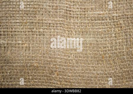 A close-up of a coarse linen fabric with a large canvas weave, showcasing its natural texture and rustic charm. The thick weave and organic Stock Photo