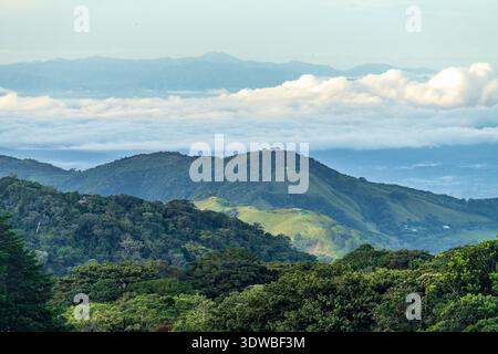 View west from Monteverde resort at sunrise over the hills towards Pacific ocean with sun breaking through clouds Stock Photo