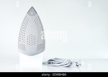 New iron with electrical cable on white background, Modern household appliances to help with daily routine and chores Stock Photo