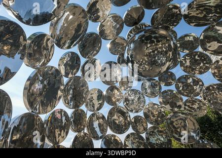 A dense arrangement of polished stainless steel spheres in an art installation, creating a repetitive pattern of reflections and geometric shapes. Stock Photo