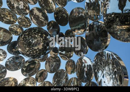Detail shot of multiple chrome spheres connected in a large art structure, emphasizing the metallic surface and distorted reflections. Stock Photo