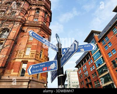 Blue street signs point visitors toward key Manchester landmarks in a historic urban setting. Stock Photo