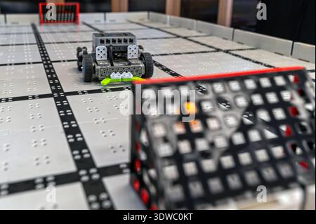 Small robots compete in a technology display at a robotics event in a classroom setting Stock Photo