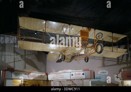 Curtiss D-III Headless Pusher (1912) was an American pusher biplane developed by the G.H. Curtiss Manufacturing Company and powered by a 50-horsepower Curtiss V-8 engine. The Headless variant eliminated the forward elevator after an accident involving exhibition pilot Lincoln Beachey. The archival image documents the fabric-covered airframe with rear elevators, orange struts, and wheeled landing gear. Stock Photo