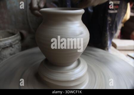 Indian artisan forms a clay pot on a fast‑spinning potters' wheel in Delhi, India, showing traditional pottery making (New Delhi 2019). Stock Photo