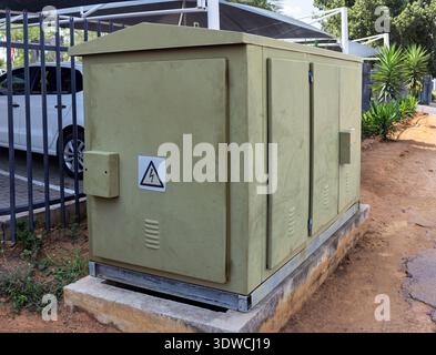 outdoor compact secondary substation, also known as an electrical distribution box or feeder pillar, with a high voltage warning symbol on the door. T Stock Photo