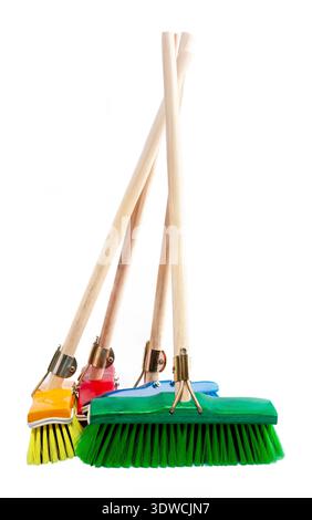 group of four colorful plastic and wood brooms for home cleaning, including green, blue, red, and yellow heads, leaning together on a white background Stock Photo