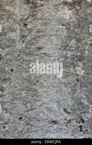 Textured gray stone surface with visible natural patterns and small holes, suitable for backgrounds or architectural design elements in various Stock Photo