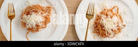 Two Plates of Spaghetti Pasta Topped with Grated Cheese on Wooden Table Stock Photo