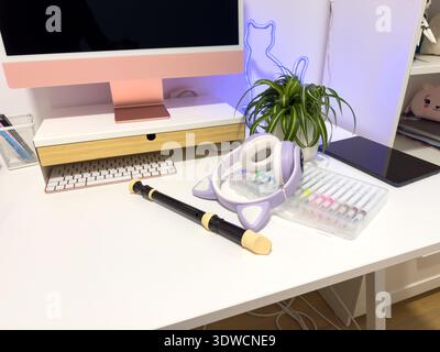 Modern bright home office setup featuring a pink desktop computer, musical instrument, and colorful art supplies on a white desk. This conceptual work Stock Photo