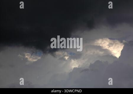 Dramatic dark storm clouds fill the sky as shafts of light break through heavy overcast layers, creating a moody, powerful atmosphere that suggests an Stock Photo