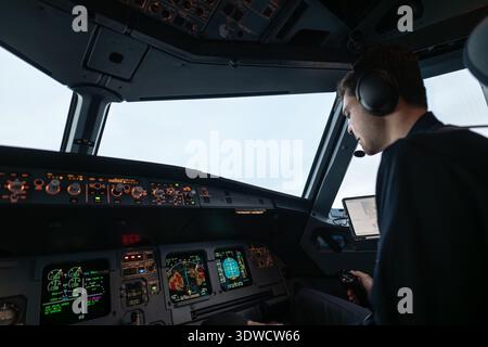 Pilot operating flight controls and looking at cockpit instruments in an aircraft Stock Photo