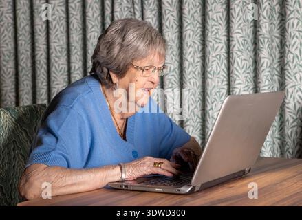86 year old grandmother using a laptop to keep in touch with her family Stock Photo