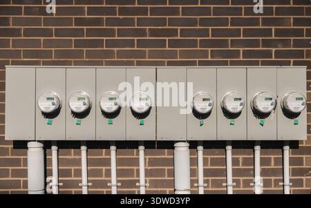 Row of modern electric utility meters on brick wall for residential energy measurement Stock Photo