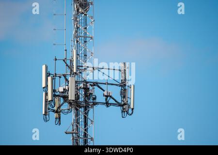 Close-up view of cellular tower antennas and telecom equipment against clear blue sky Stock Photo