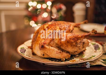 Golden roasted holiday turkey on a festive table with warm Christmas lights in the background, traditional for Christmas and Thanksgiving in the USA. Stock Photo
