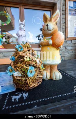 Ceramic bunny with orange Easter egg on rustic table in cafe setting Stock Photo
