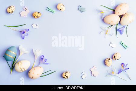 Easter eggs with crocus flowers and rabbit shapes on light purple background. Top view, flat lay, copy space. Stock Photo