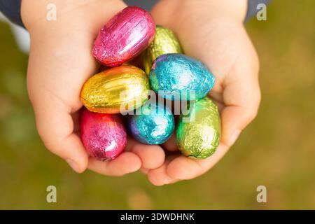 Chocolate eggs in foil Easter bright decor. Eggs in the hands of a child Easter eggs. Stock Photo