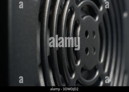 matte black textured pc power supply fan grid, dark metallic surface with rough powder-coated finish, closeup angle view with soft focus Stock Photo