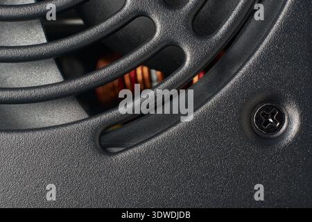 matte black metal pc power supply fan grid surface closeup, curved air vents and black mounting screw on protective casing, full frame texture Stock Photo