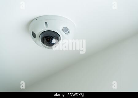 A ceiling mounted security camera installed in a modern house in London, United Kingdom. The sleek, minimalist design blends with the neutral colored Stock Photo