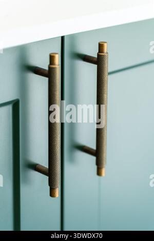 Close up of sleek, textured gold cabinet handles on matte doors in a contemporary London home interior, highlighting elegant design and sophisticated Stock Photo