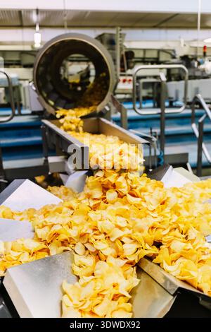 Automated process of potato chip production in a modern factory, showcasing machinery in action and the efficient manufacturing of crispy, golden chip Stock Photo