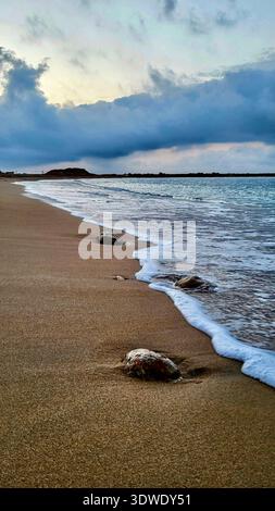 Idyllic and peaceful beach scene on the Costa Brava featuring white foaming waves rolling onto the shore in soft, cozy morning light. Stock Photo