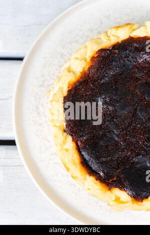 A delicious Basque cheesecake with a perfectly toasted layer, featuring a rich, creamy texture. Served on a white plate, offering a delightful dessert Stock Photo