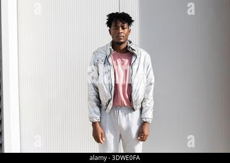 A fashionable individual in a silver jacket exuding a modern and futuristic vibe. The stylish outfit combines metallic textures with a confident expre Stock Photo