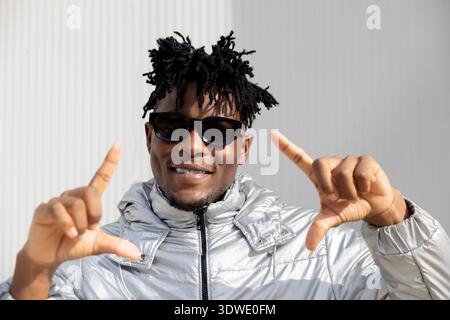 A stylish man wearing sunglasses and a silver jacket, catching the essence of futuristic fashion with a confident expression and cool demeanor against Stock Photo