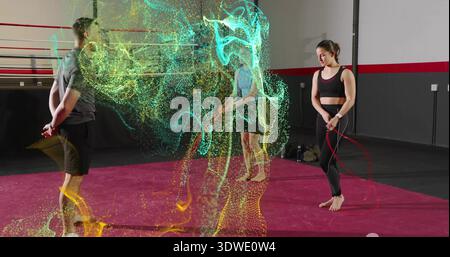 Holding jump rope, right woman wearing black gear barefoot on red mat, particle trails, copy space Stock Photo