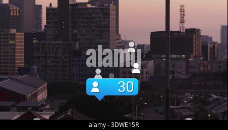 Floating blue notification bubble showing 30 and three white user icons over city skyline at dusk Stock Photo