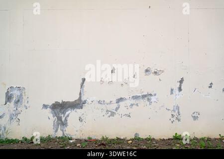 Weathered Off-White Exterior Wall Surface with Visible Cement Patches and Cracks Stock Photo