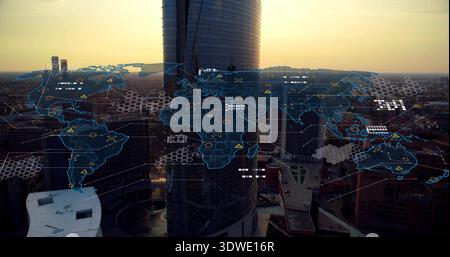 Displaying holographic world map overlay over rooftops, reflecting sunset on cylindrical tower Stock Photo