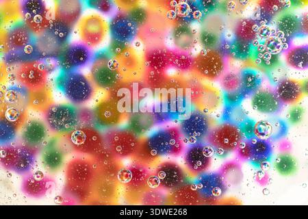 A mesmerizing display of clear bubbles floating against a backdrop of vibrant, multi-colored circles, creating an abstract journey to the center of co Stock Photo