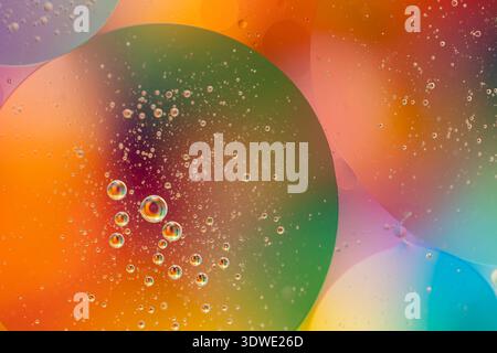 A mesmerizing close-up of colorful bubbles suspended in liquid against a vibrant backdrop. The rainbow-like spectrum creates a captivating abstract ar Stock Photo