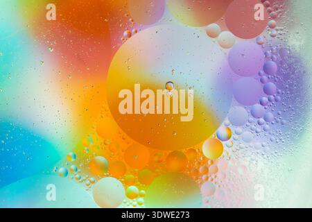 Dive into a world of vibrant color with this abstract image of bubbles suspended in oil. Featuring a spectrum of orange, blue, and purple hues for a c Stock Photo