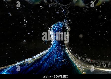 An artistically captured image of colorful bubbles forming unique shapes and patterns in a dark liquid environment, showcasing the interplay of light Stock Photo