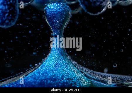 A close-up of vibrant blue bubbles captured in liquid, creating an artistic and original abstract composition. The contrast with the dark background h Stock Photo