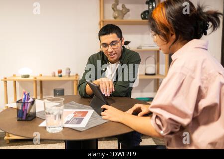 Two colleagues engaged in a productive discussion at a coworking space, sharing ideas and collaborating effectively. A modern office environment foste Stock Photo