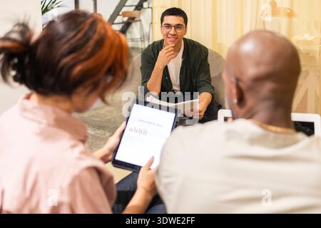 A diverse group of young professionals engages in a collaborative discussion within a modern coworking office. The atmosphere is creative and focused, Stock Photo