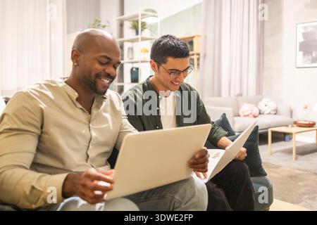 Two colleagues using laptops in a cozy coworking office, collaborating on a project. The relaxed environment encourages creativity and teamwork, enhan Stock Photo