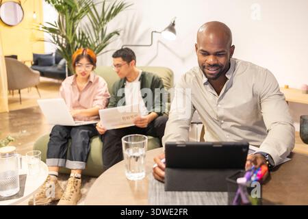 A diverse team of professionals working together in a modern coworking space. Engaged in discussion and collaboration, fostering creative teamwork in Stock Photo