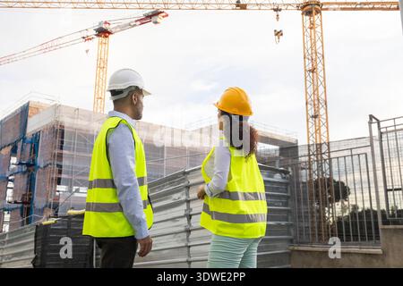 Two construction professionals wearing reflective vests and hard hats ...