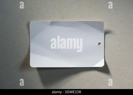 Wrinkled Empty white price tag paper on off-white background Stock Photo