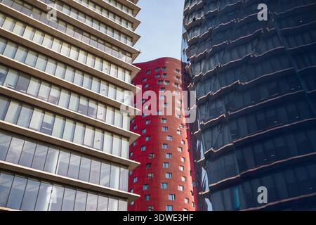 Modern office buildings with distinctive red and glass facades form a striking architectural contrast. Their geometric patterns create an urban visual Stock Photo